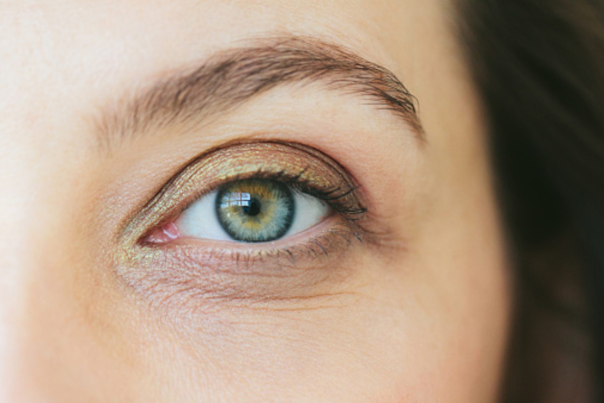 Close-up of a green eye with detailed iris and eyebrow.