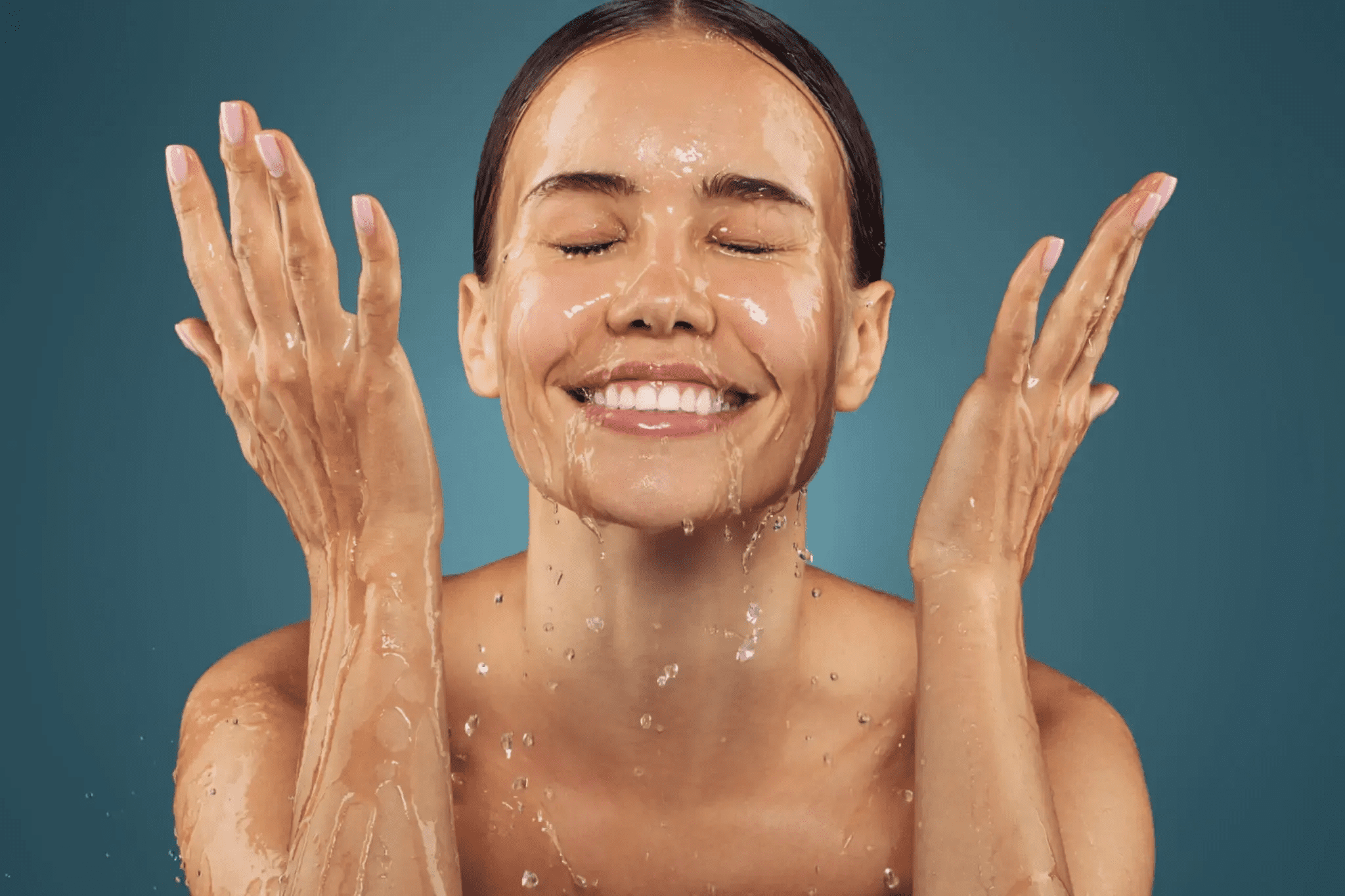 Woman happily washing her face with water.