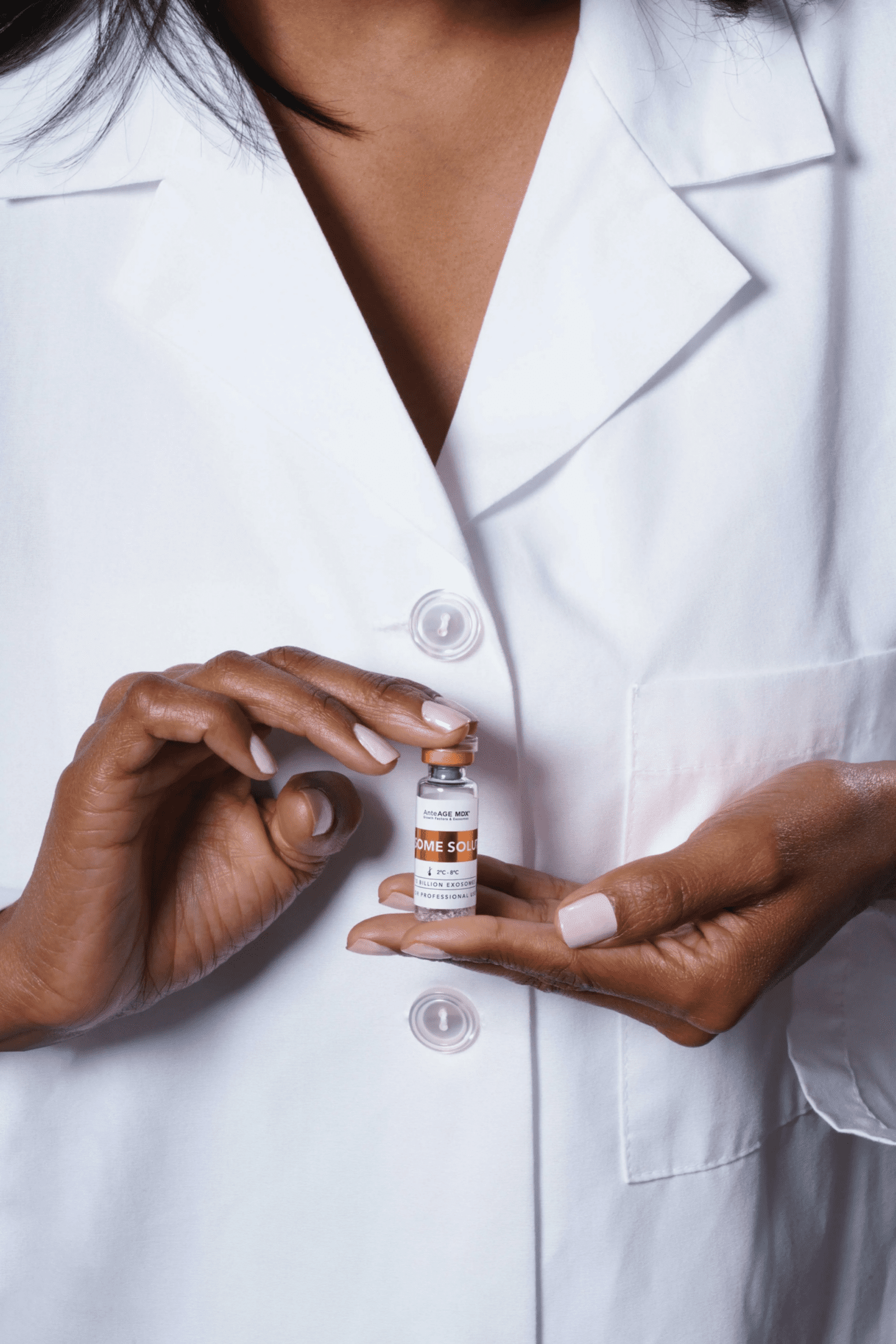 A healthcare professional holding a small medicine vial.