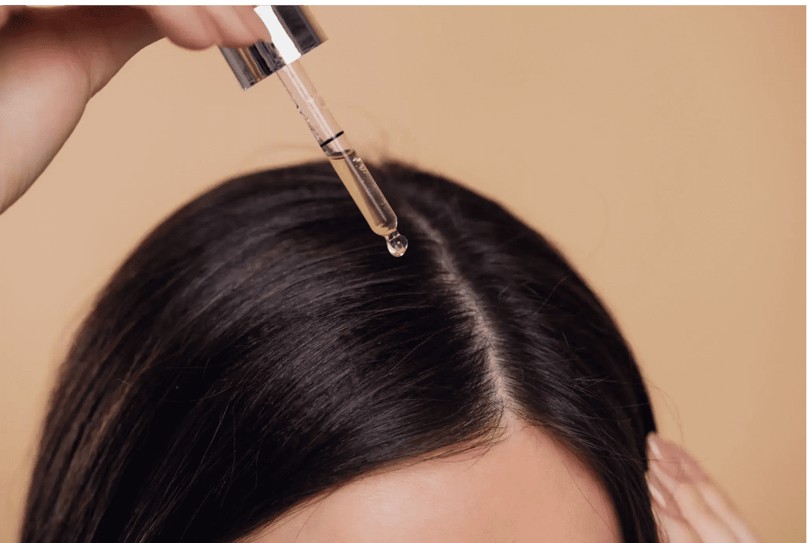 Applying hair serum to the scalp for hair care.
