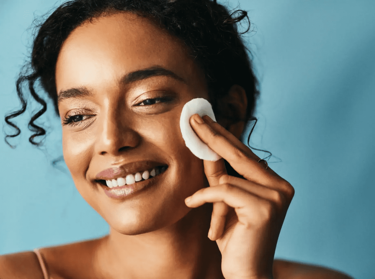 Woman gently cleansing her face with a cotton pad.
