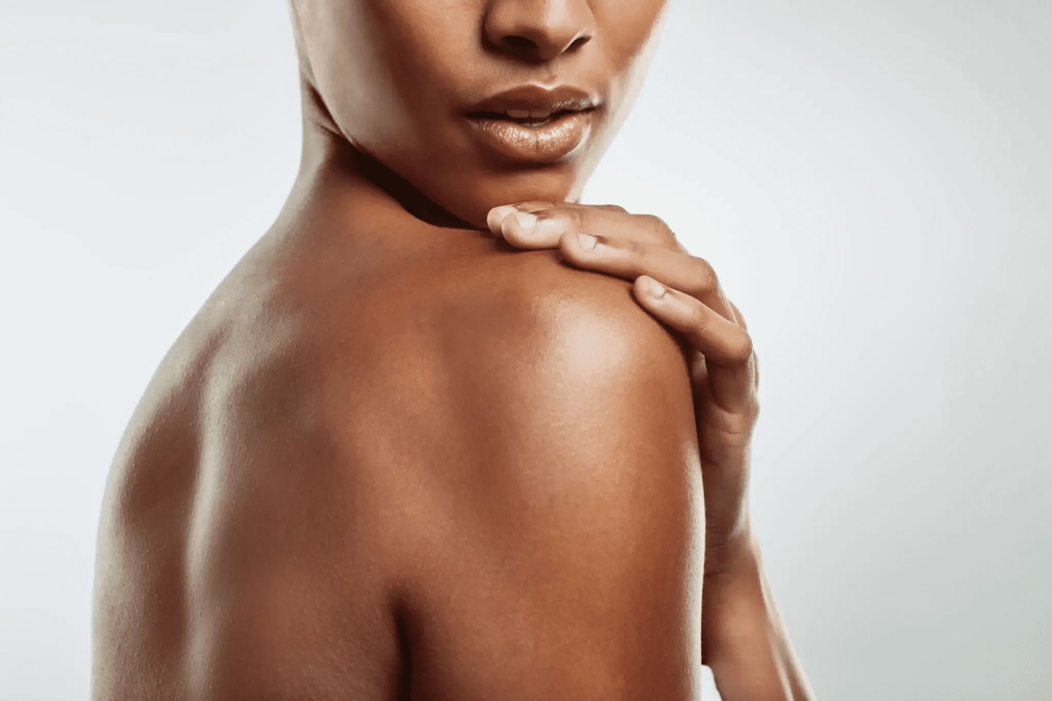 Close-up of a person gently touching their shoulder.