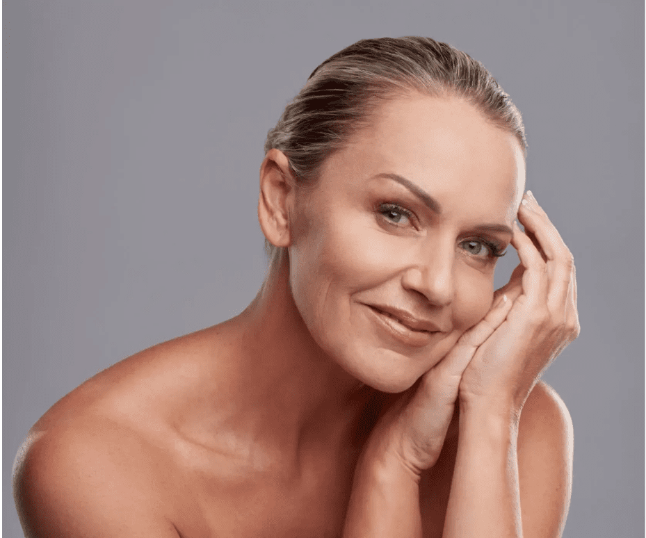 Smiling mature woman with clear skin resting her face on her hand.