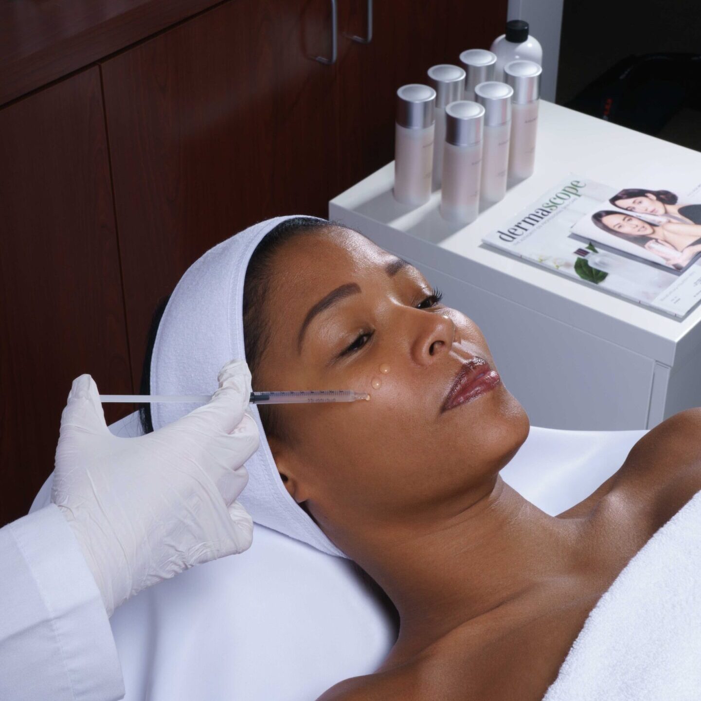 Woman receiving a facial dermal filler injection in a clinic.