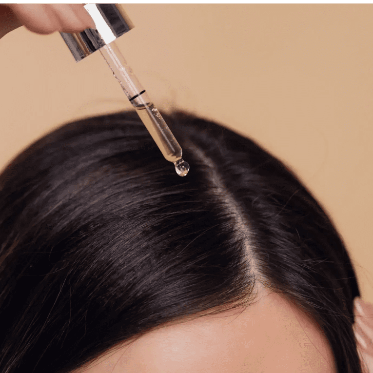 Applying hair serum to the scalp for hair care.