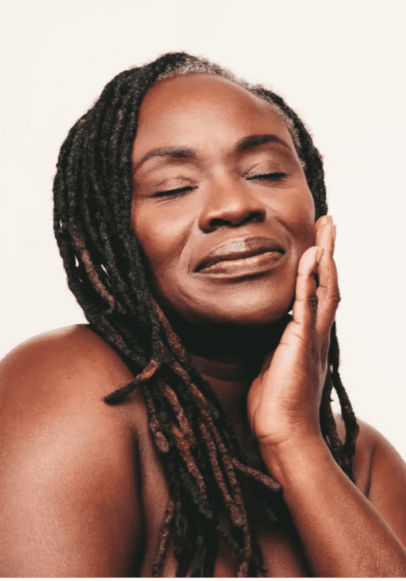 A serene woman with closed eyes gently touching her face.