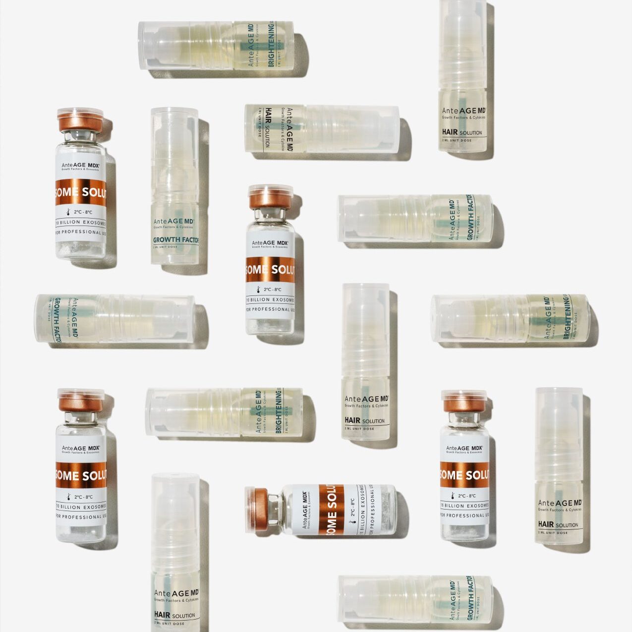 Pattern of vaccine vials and syringes laid out on a white surface.