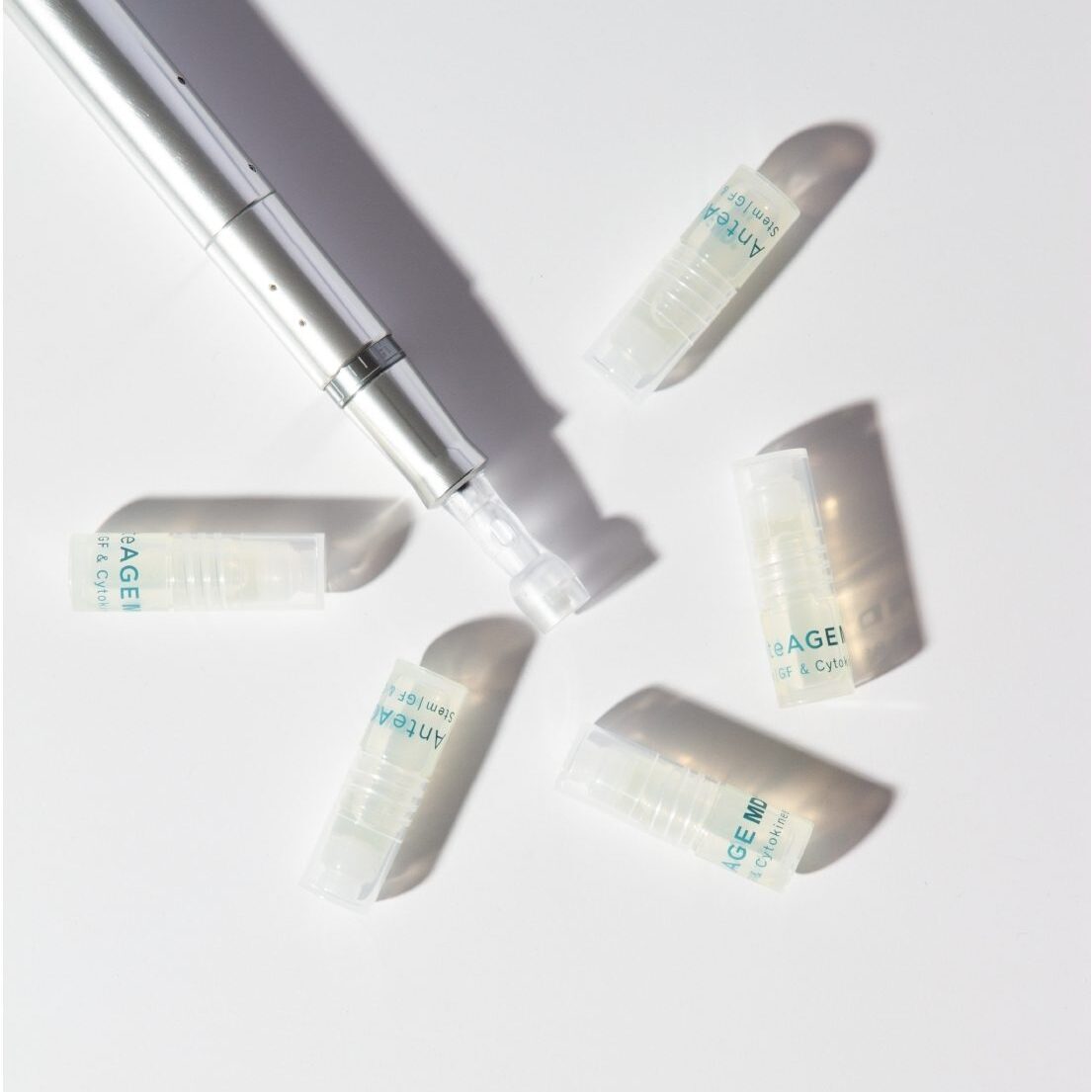 Small white bottles of skincare product scattered on a light surface.